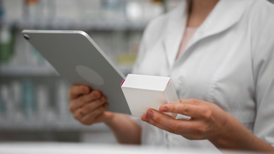 Female pharmacist with tablet checking stock in pharmacy
